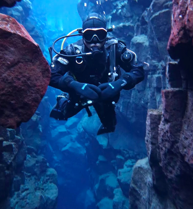 Scuba diving underwater between rock formations