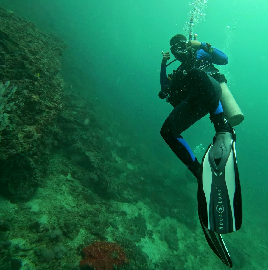 Scuba diving beside an underwater rock wall
